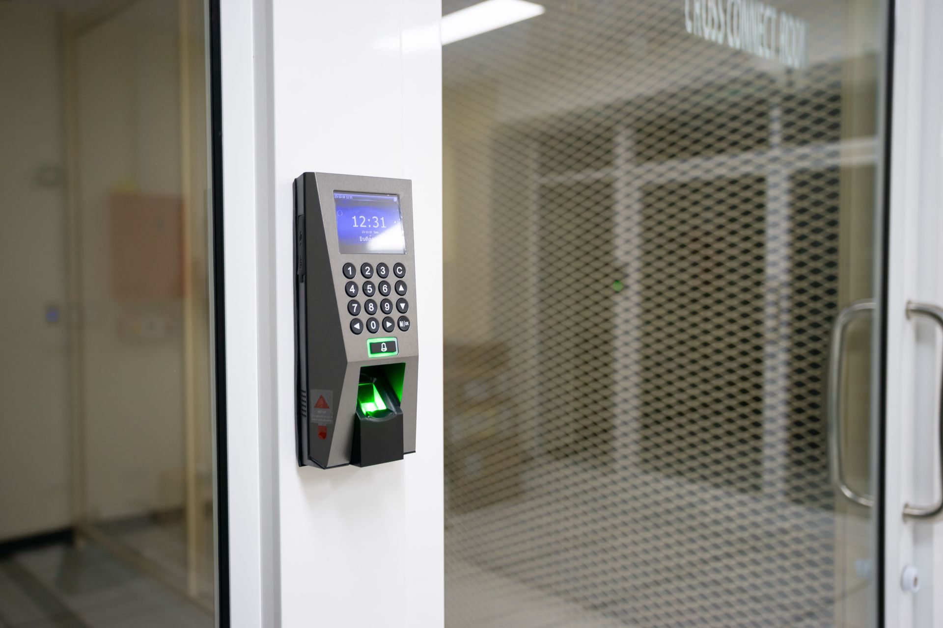 Biometric access control and attendance scanner on a corporate glass door.