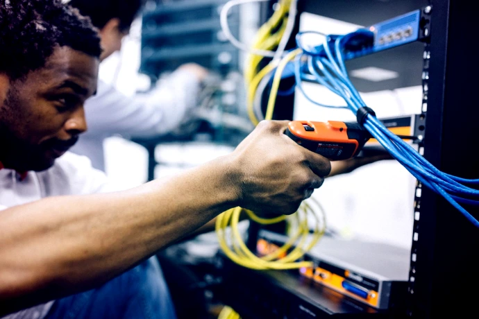 Technician neatly organizing network cabling bundles and infrastructure setup.